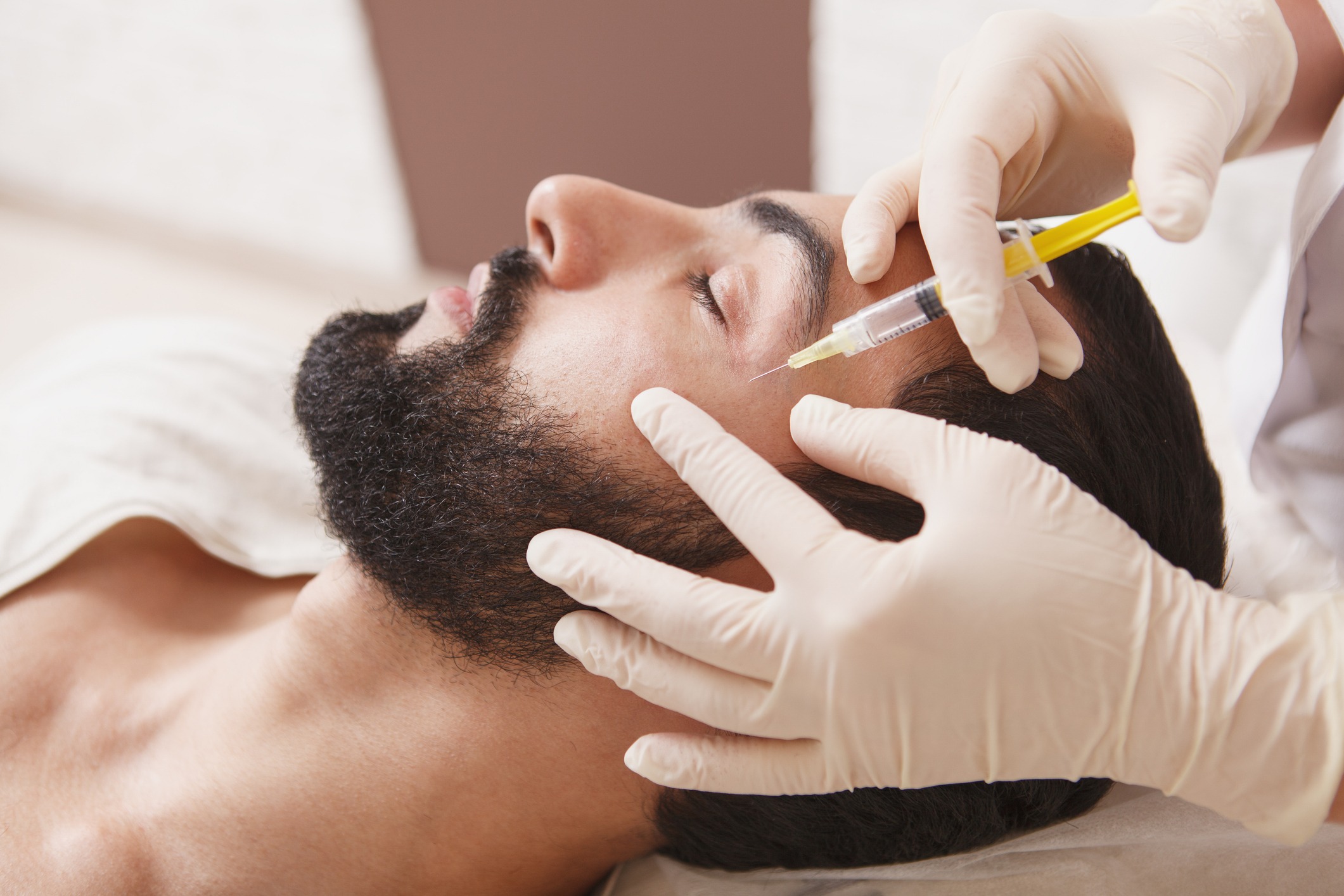 Bearded man getting anti-wrinkle face filler treatment